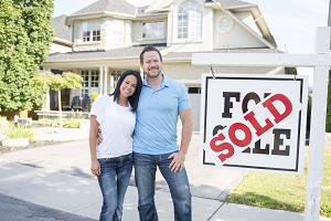 A couple standing in front of their new house